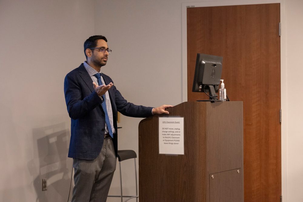 A man in a suit and tie is standing at a podium giving a presentation.