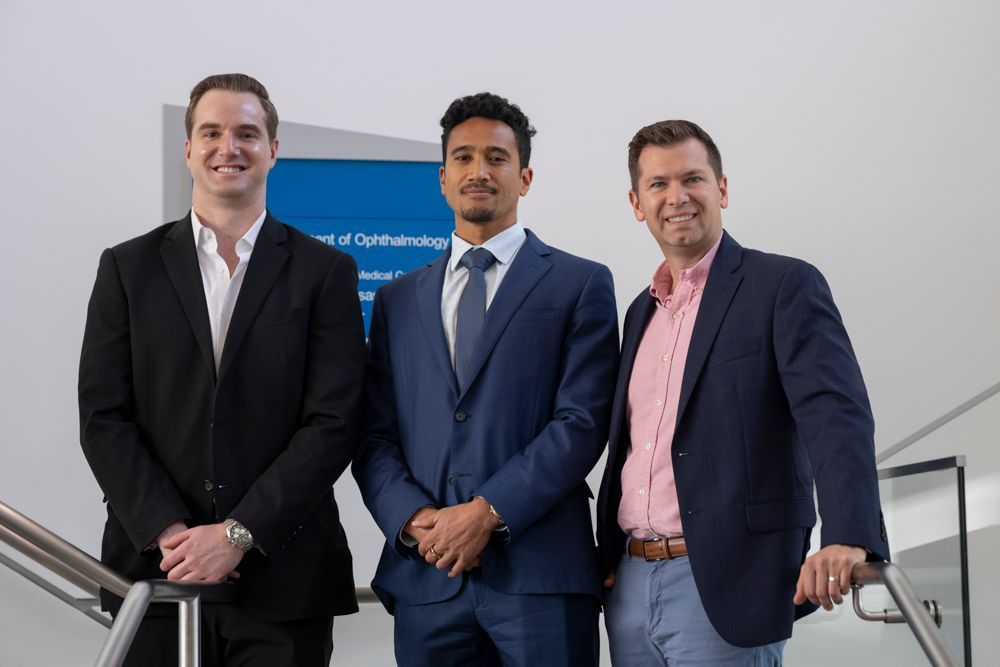 Three men in suits are standing next to each other on a set of stairs.