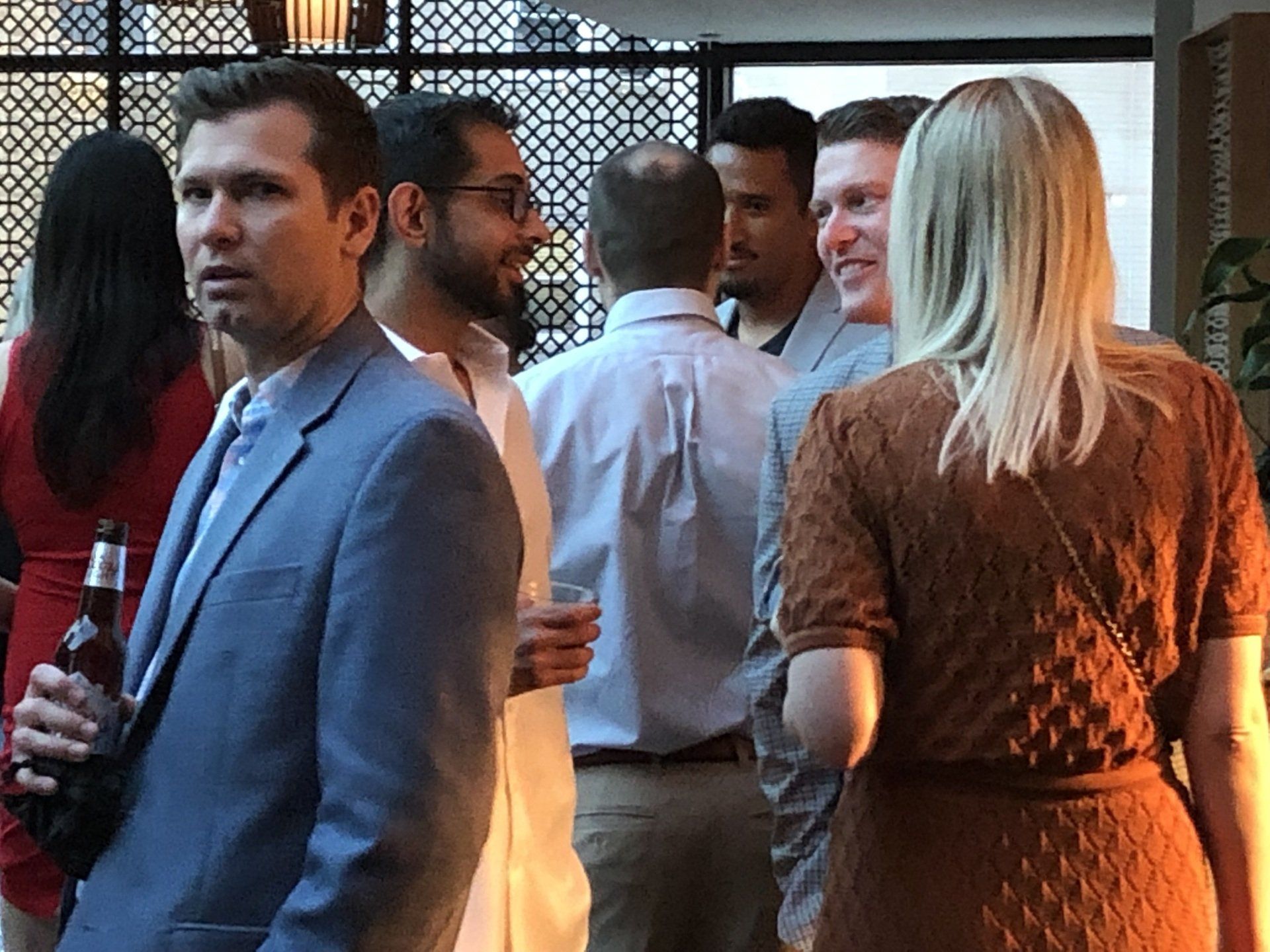 A group of people are standing in a room talking to each other.