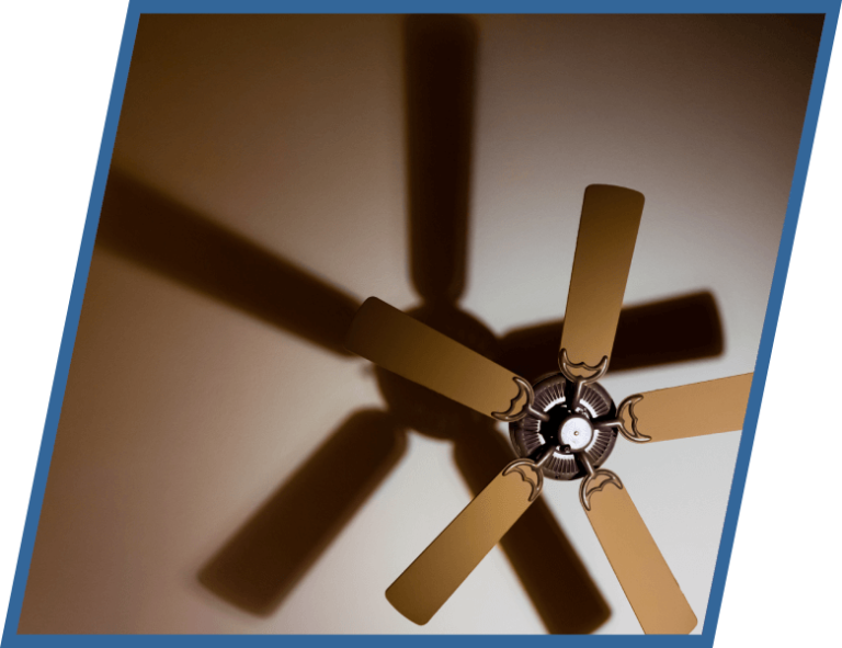 A ceiling fan is casting a shadow on the wall