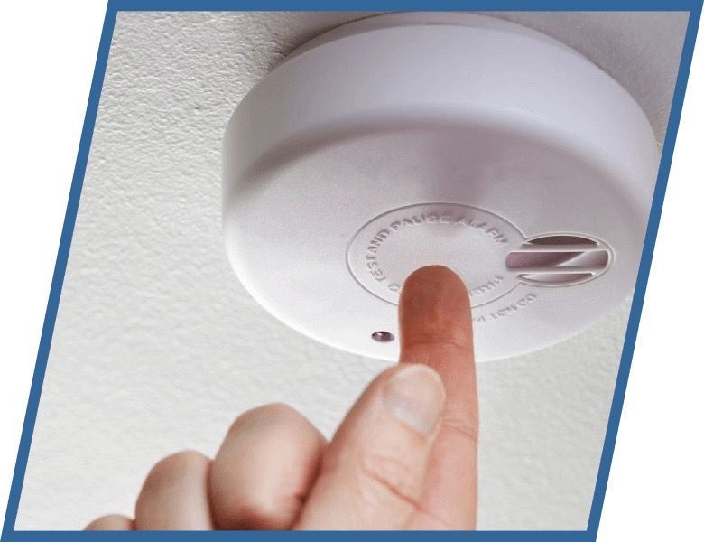 A person is pressing a button on a smoke detector