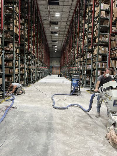 A man is using a vacuum cleaner in a large warehouse.