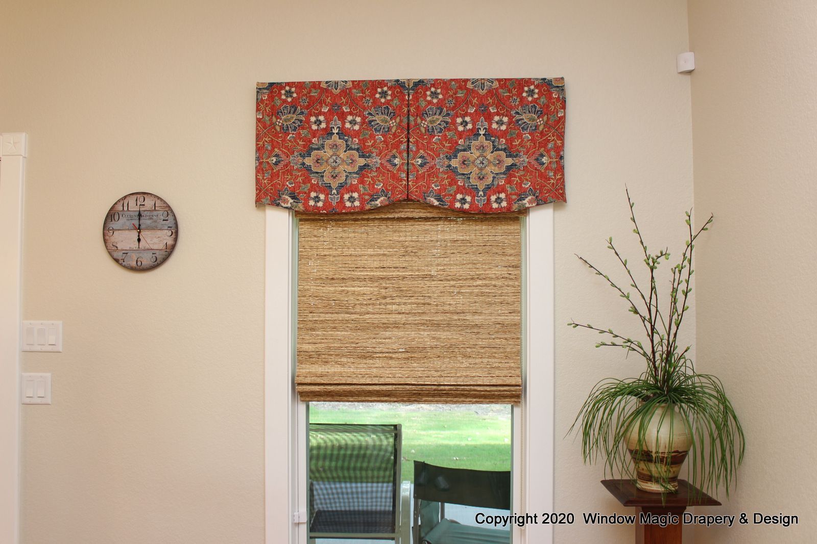 A living room with a clock on the wall and a potted plant on a table.