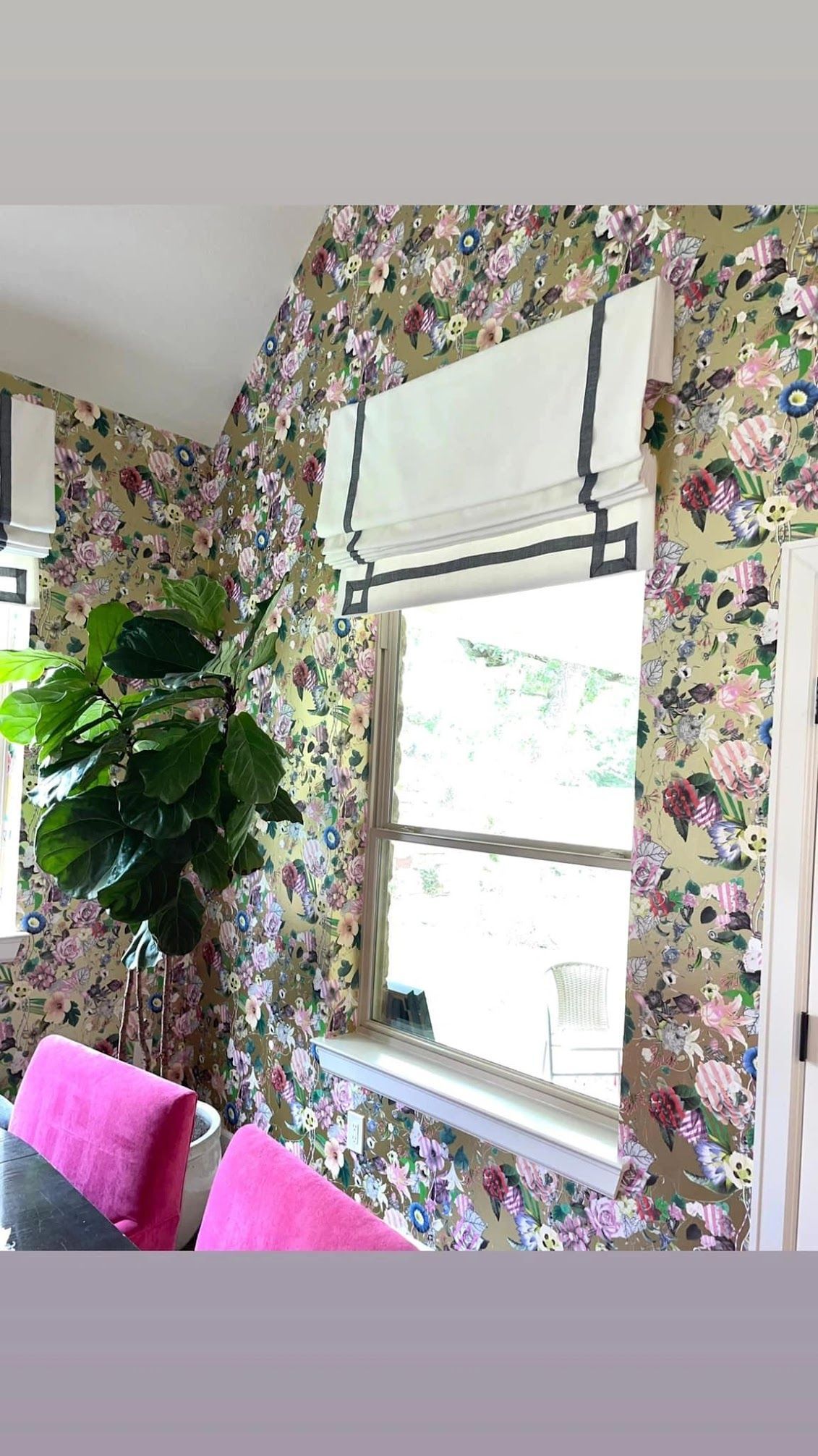 A living room with floral wallpaper and a window with roman shades.