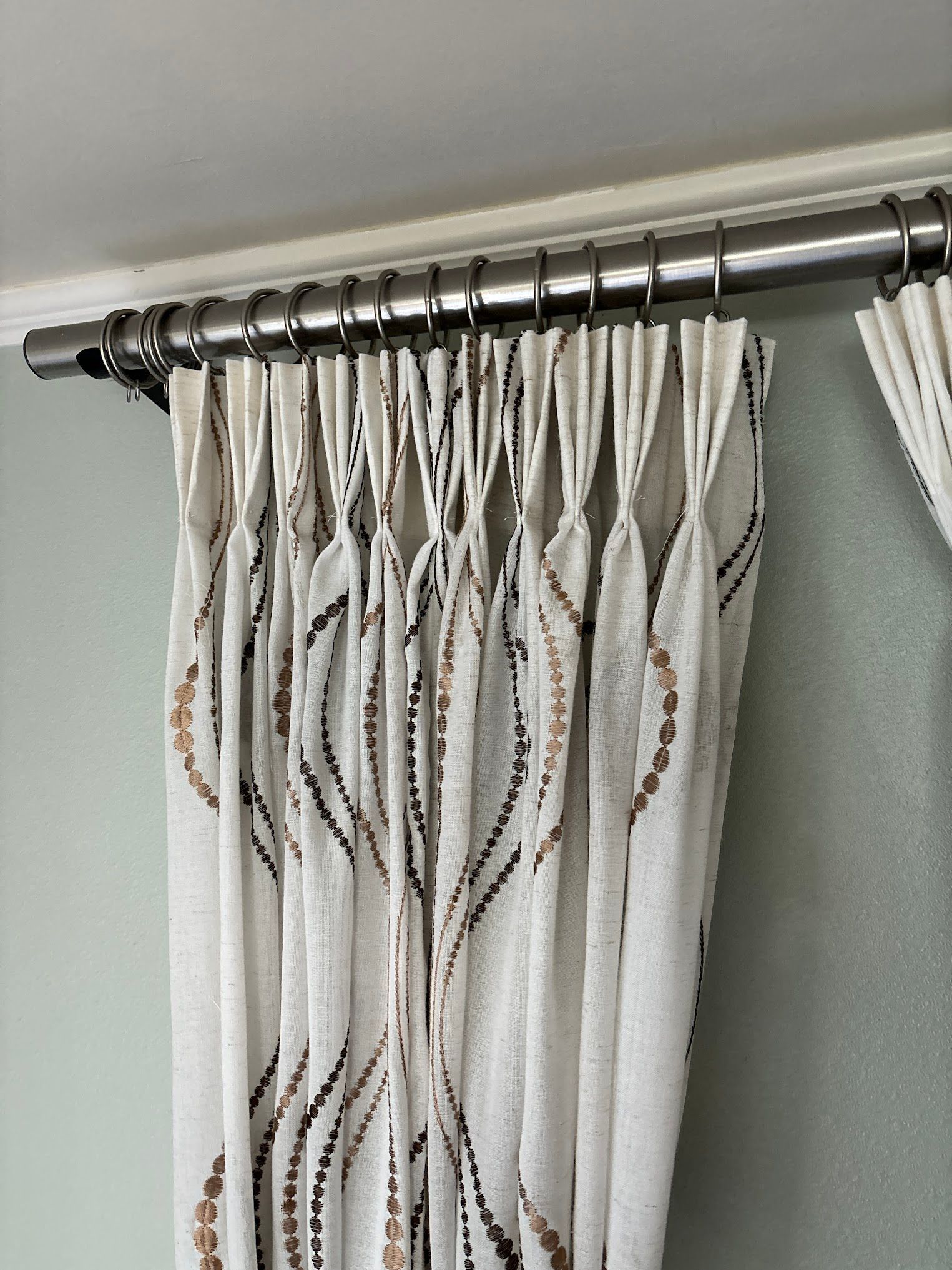 A close up of a pair of curtains hanging on a curtain rod.
