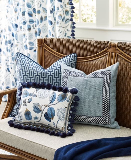A wicker couch with blue and white pillows on it