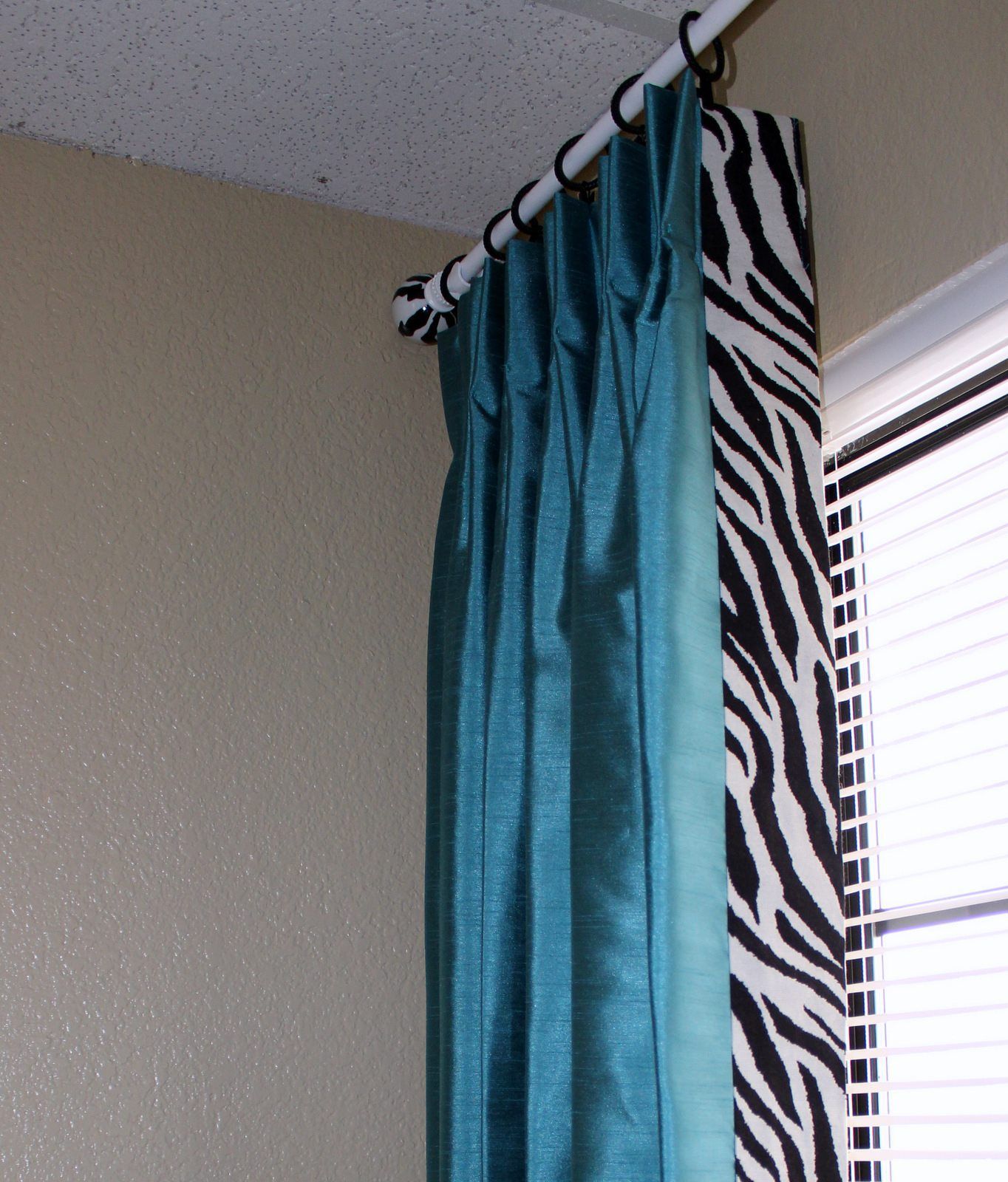 A window with a zebra print curtain and a blue curtain