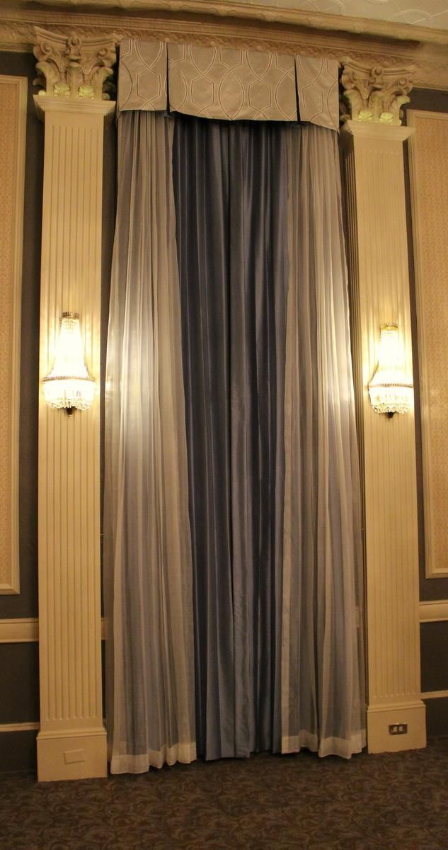 A curtain is hanging on a wall in a room with columns.