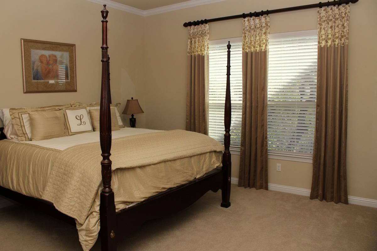 A bedroom with a four poster bed and two windows