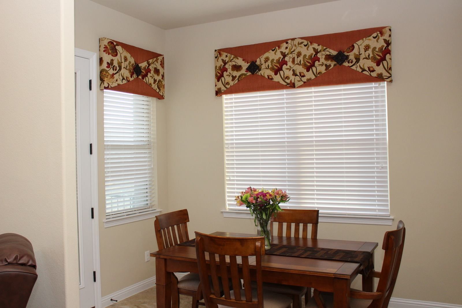 A dining room with a table and chairs and a window with blinds