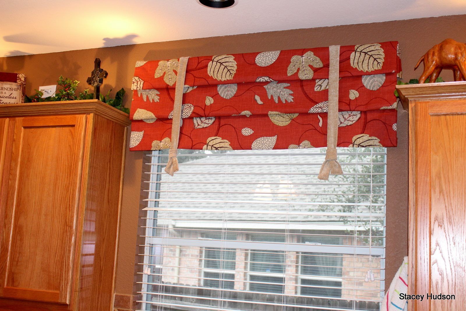 A window with blinds and a red roman shade