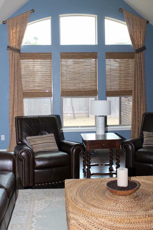 A living room with a vaulted ceiling , two chairs , a table , and a wicker coffee table.