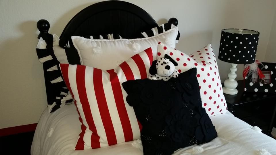 A bed with red white and black pillows on it
