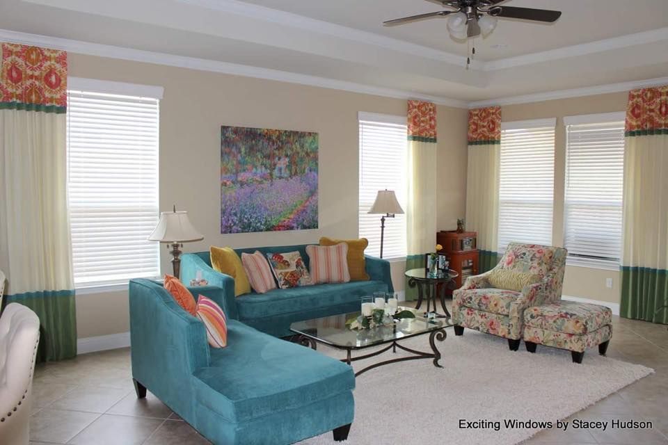 A living room with a blue couch , two chairs , a coffee table and a ceiling fan.