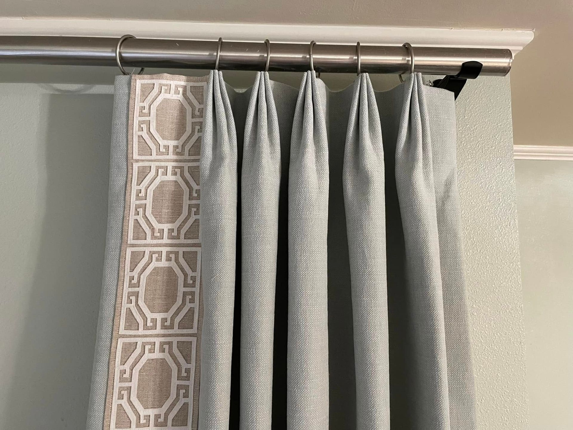 A close up of a pair of curtains hanging on a curtain rod.