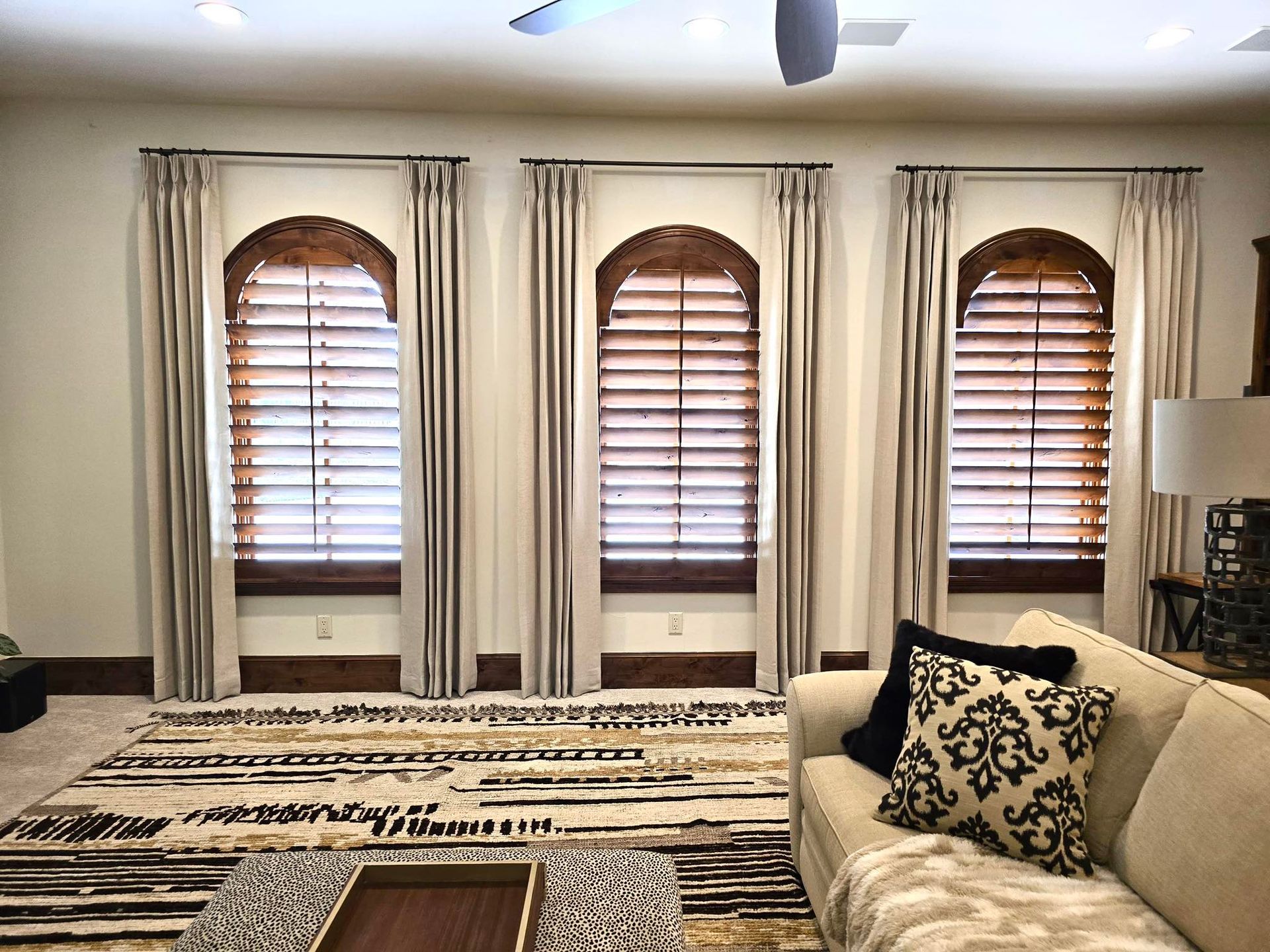 A living room with a couch , coffee table , and arched windows.