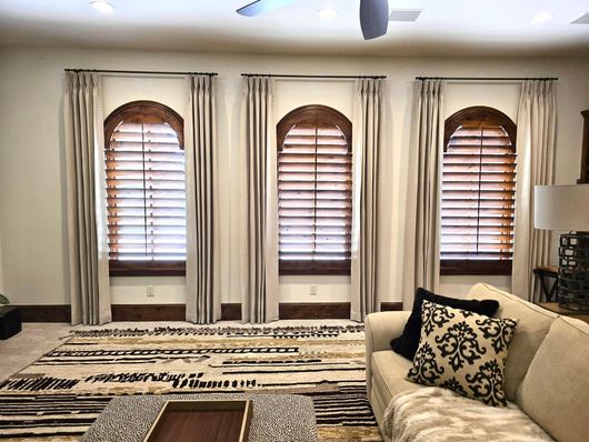 A living room with a couch , coffee table , and arched windows.