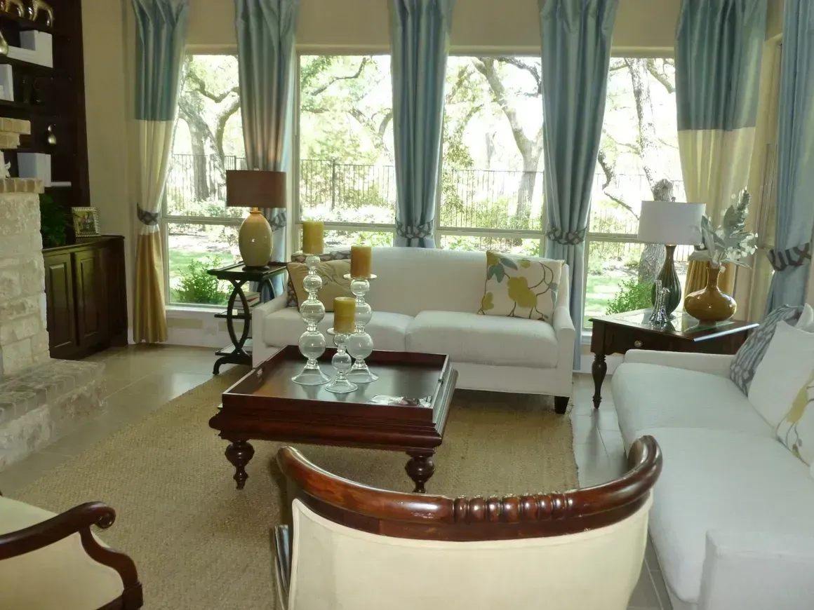 A living room with white furniture and blue curtains