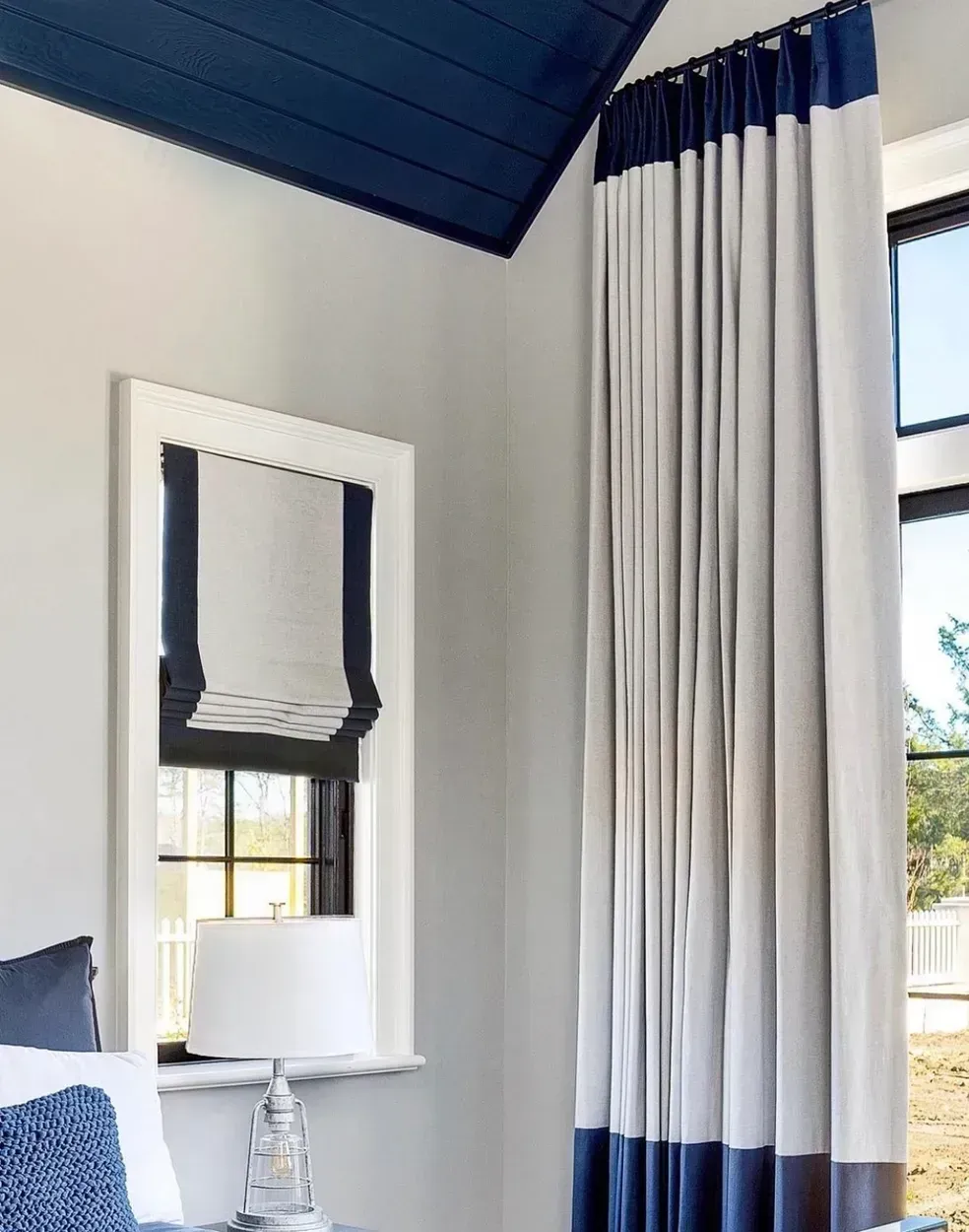 A bedroom with blue and white curtains and a blue ceiling