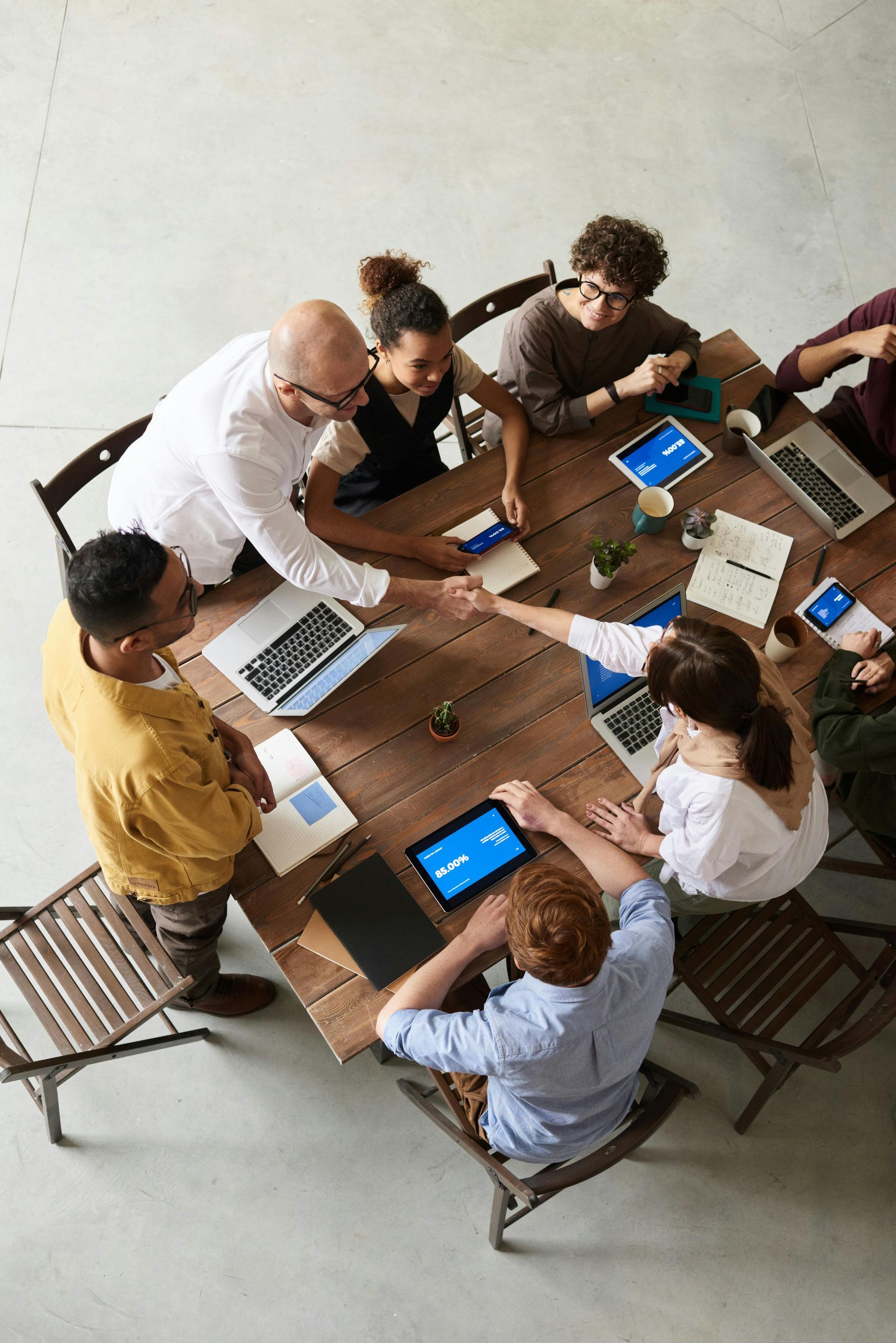 A group of people are sitting around a table shaking hands.