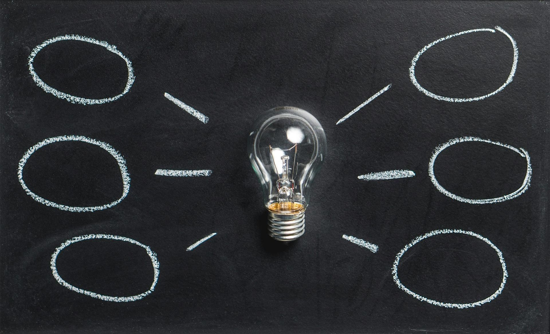A light bulb is surrounded by circles on a blackboard