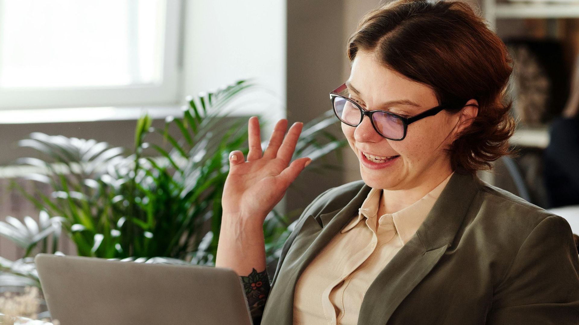 A woman wearing glasses is sitting in front of a laptop computer.