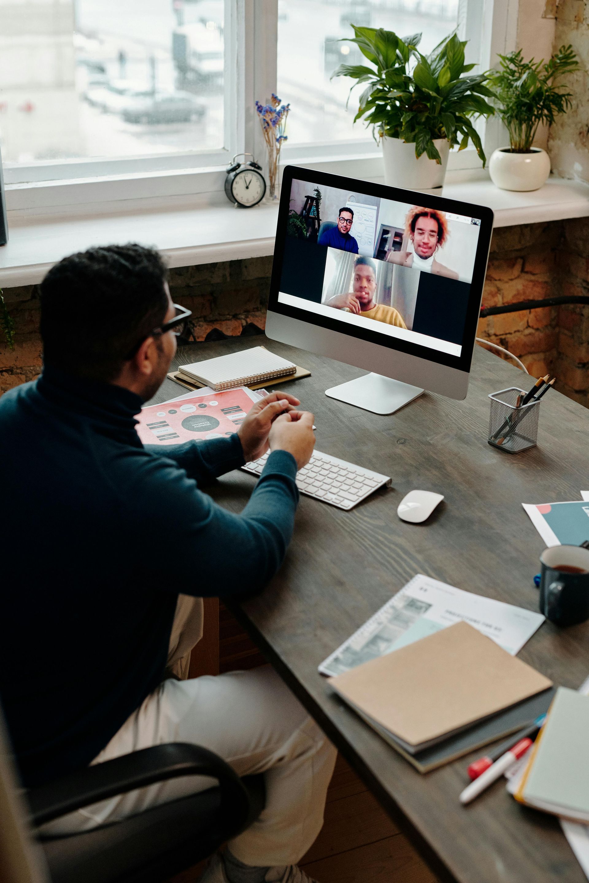 A man is sitting at a desk using a computer to have a video call.