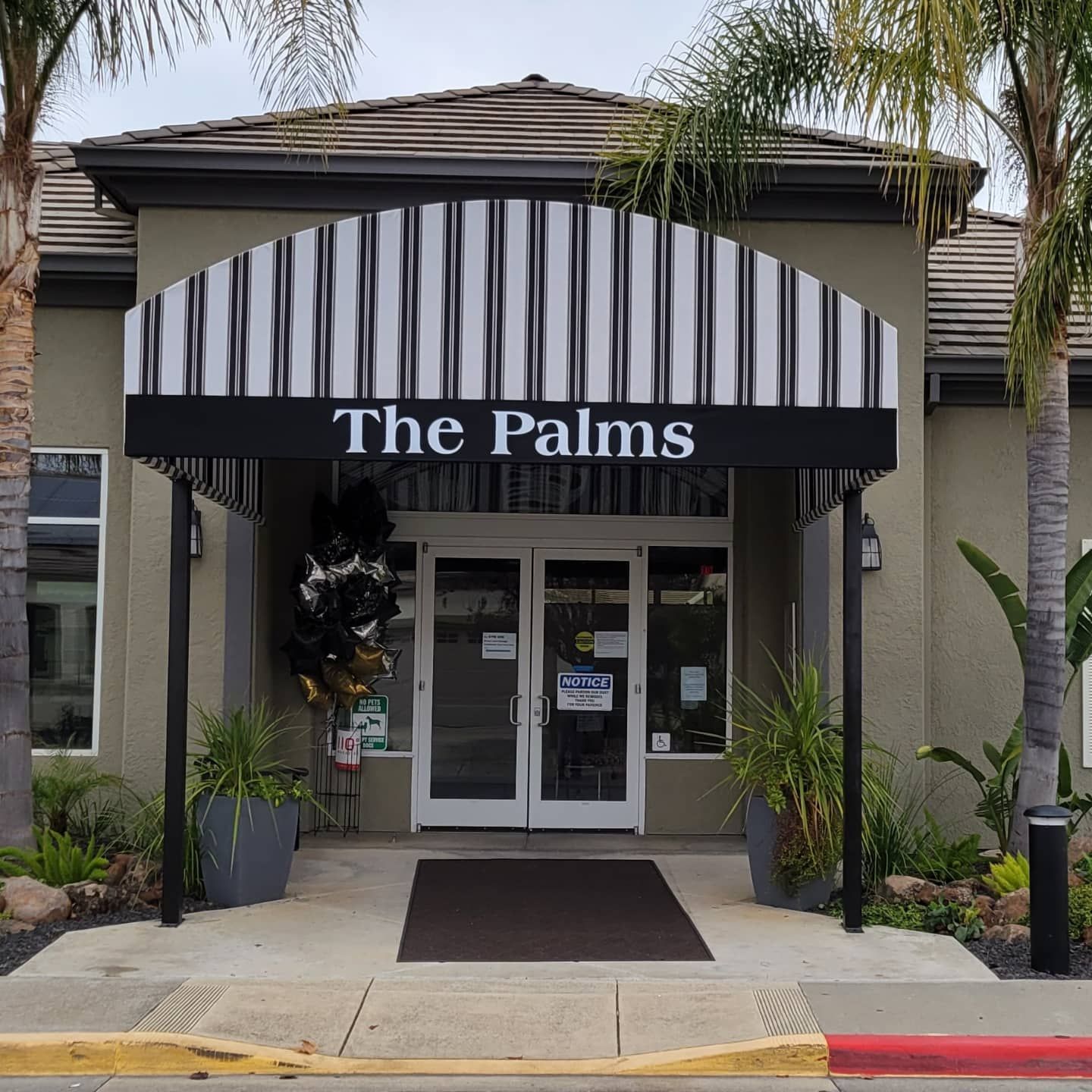 A building with a black and white awning that says the palms