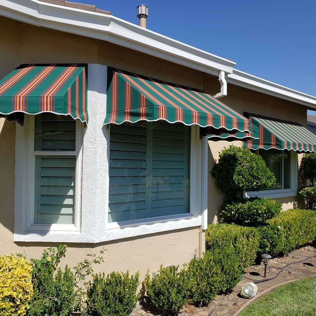 A house with a green and red awning on the windows