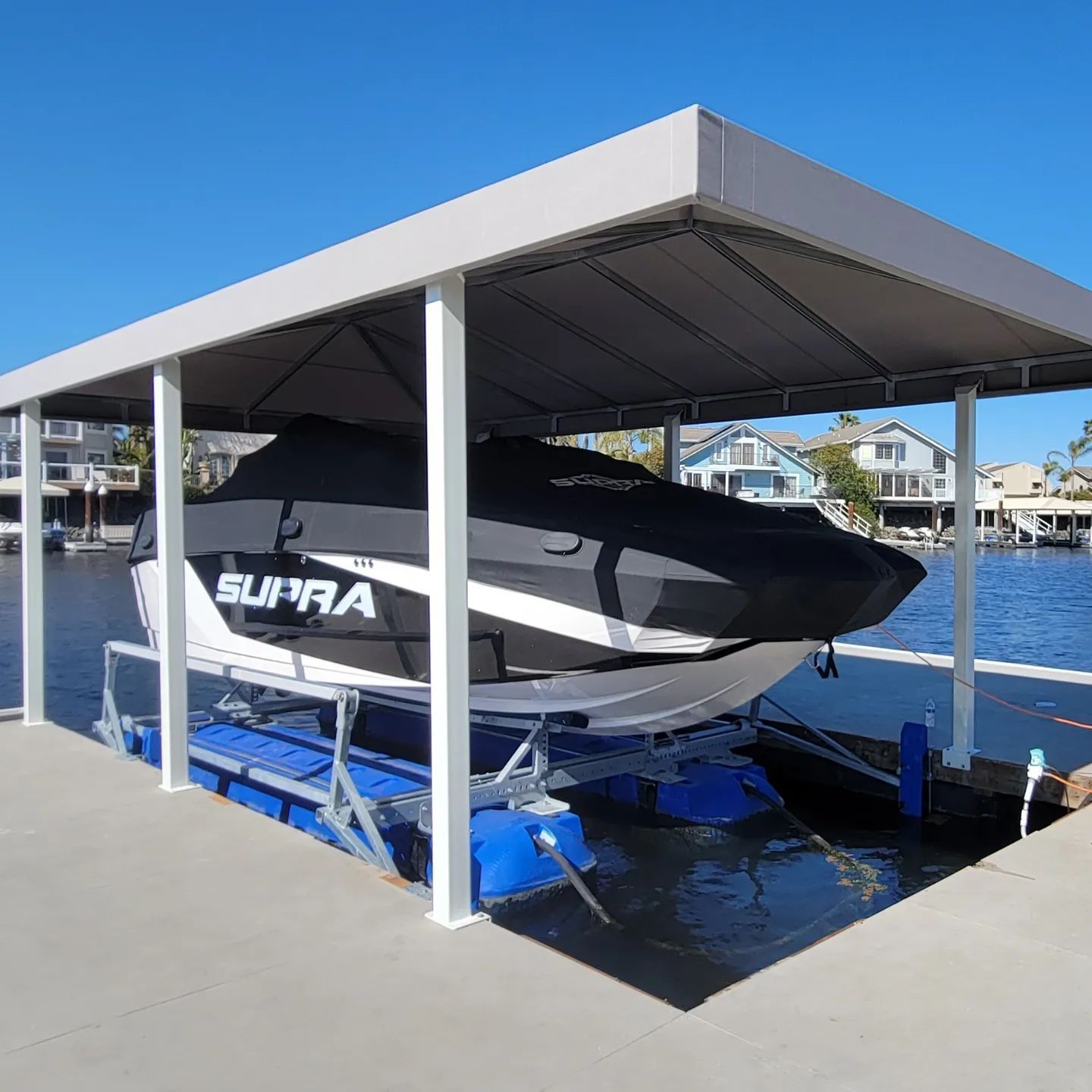 A supra boat is sitting under a canopy on a dock.