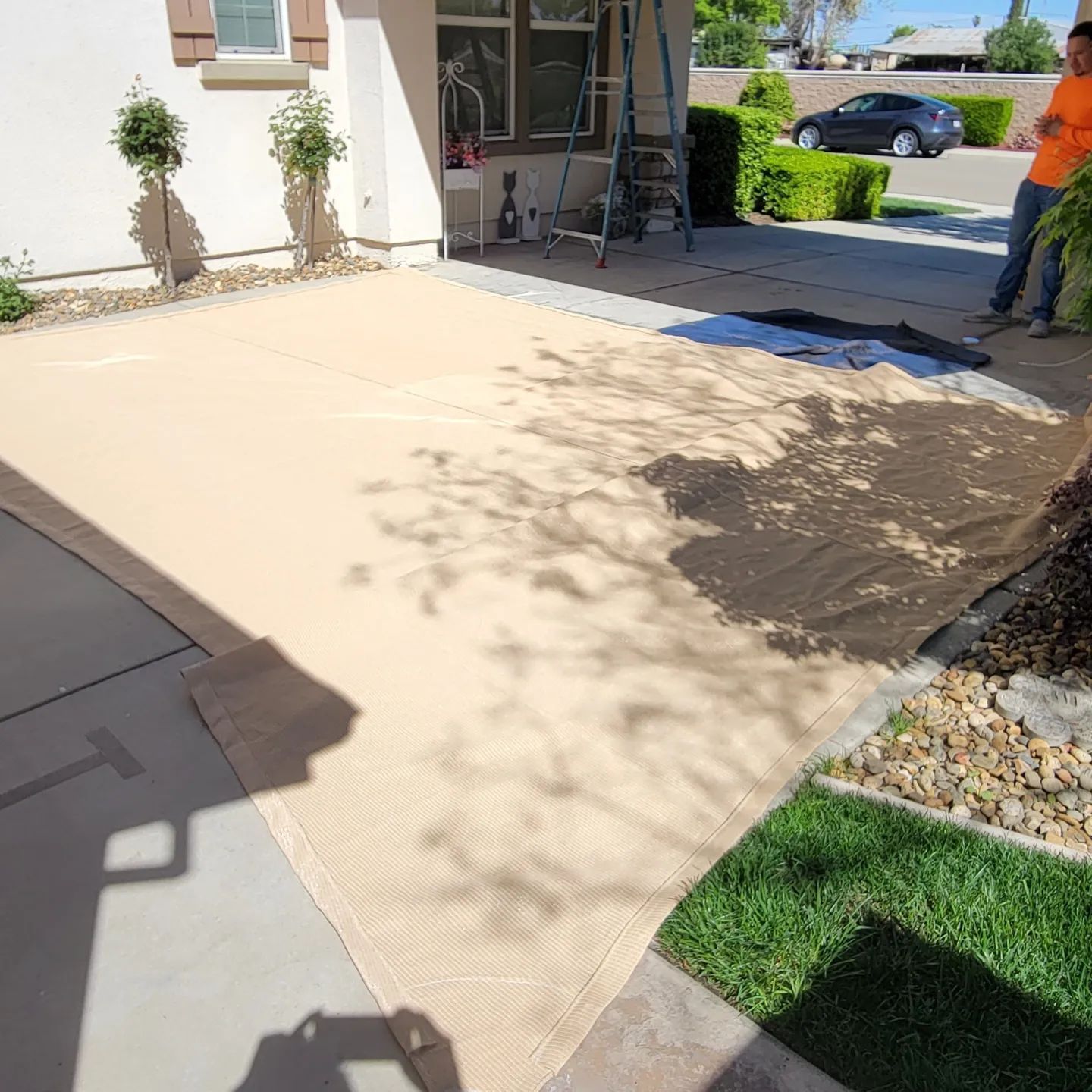 A man is standing on a concrete driveway next to a house.