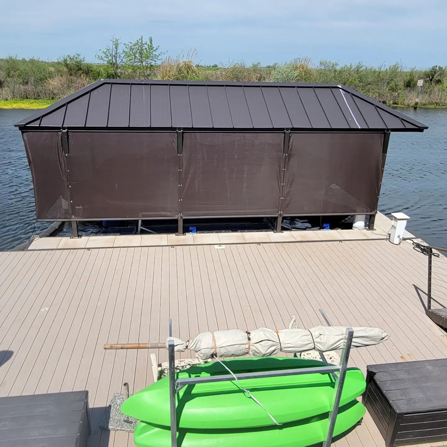 A row of green kayaks are sitting on a dock next to a building.