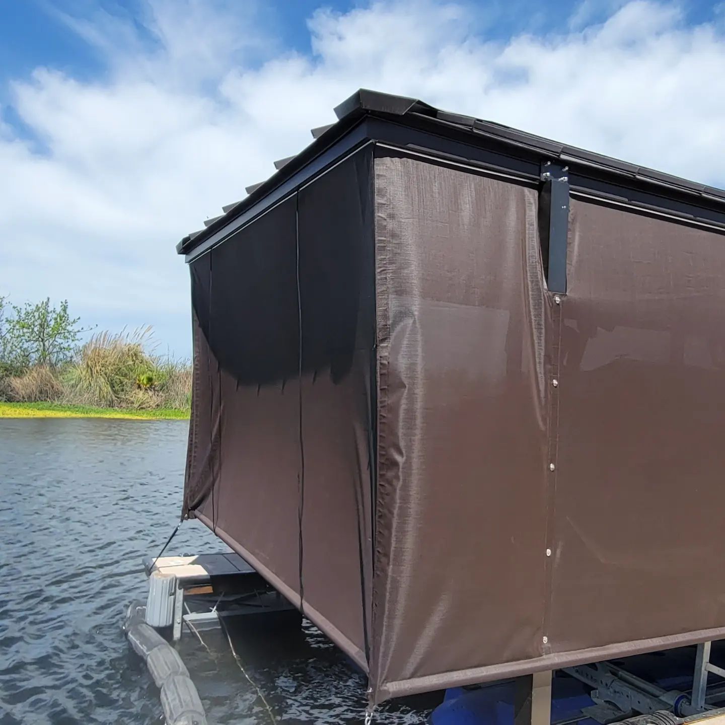 A brown shed sits on a dock in the water