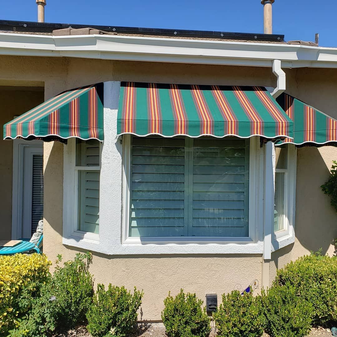 A house with a green and red awning over a window