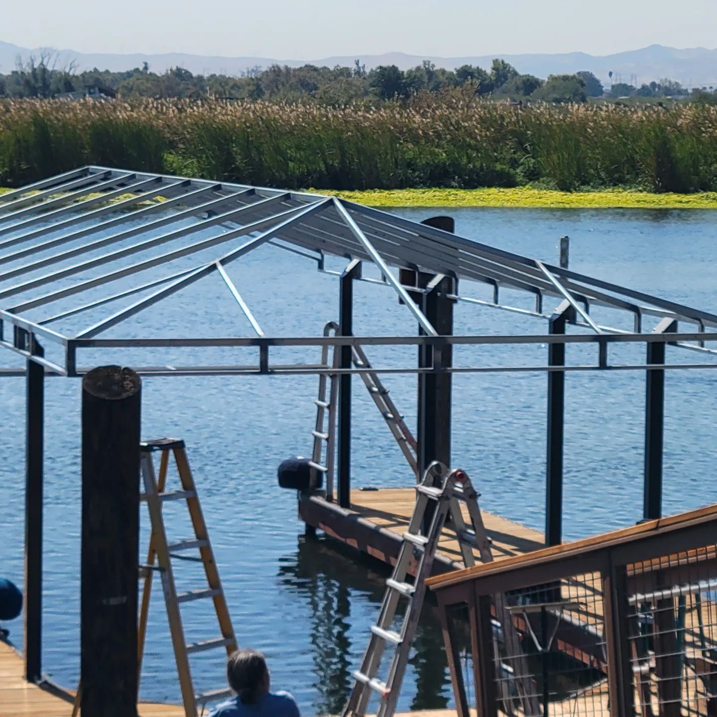 A man sits on a dock near a body of water