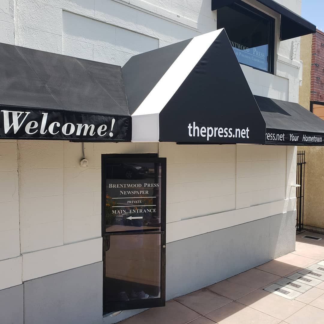 A white building with a black awning that says welcome