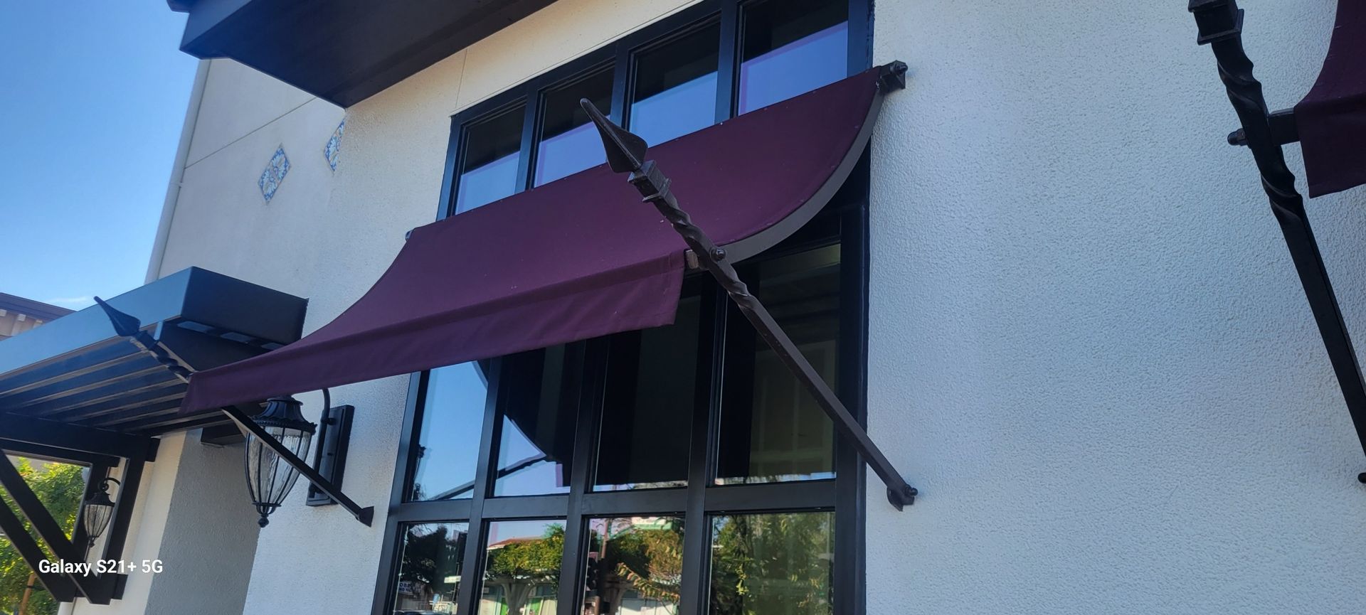 A white building with a purple awning on the windows.