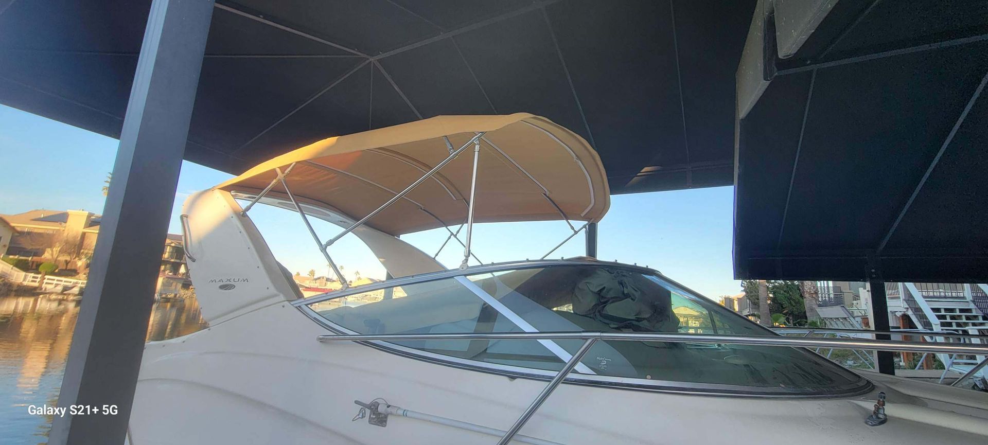 A boat with a canopy on top of it is parked under an umbrella.