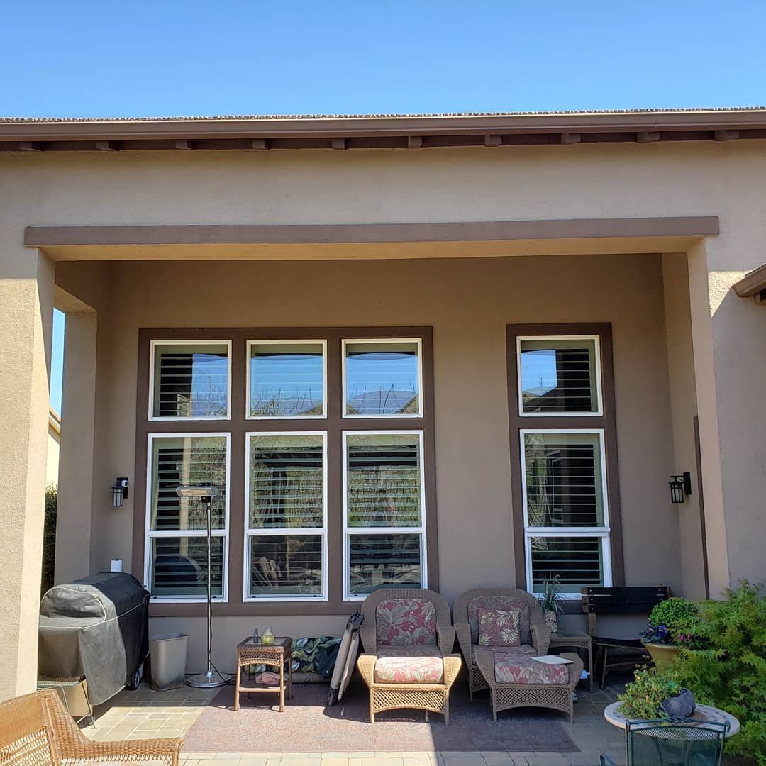 A house with a lot of windows and chairs on the patio