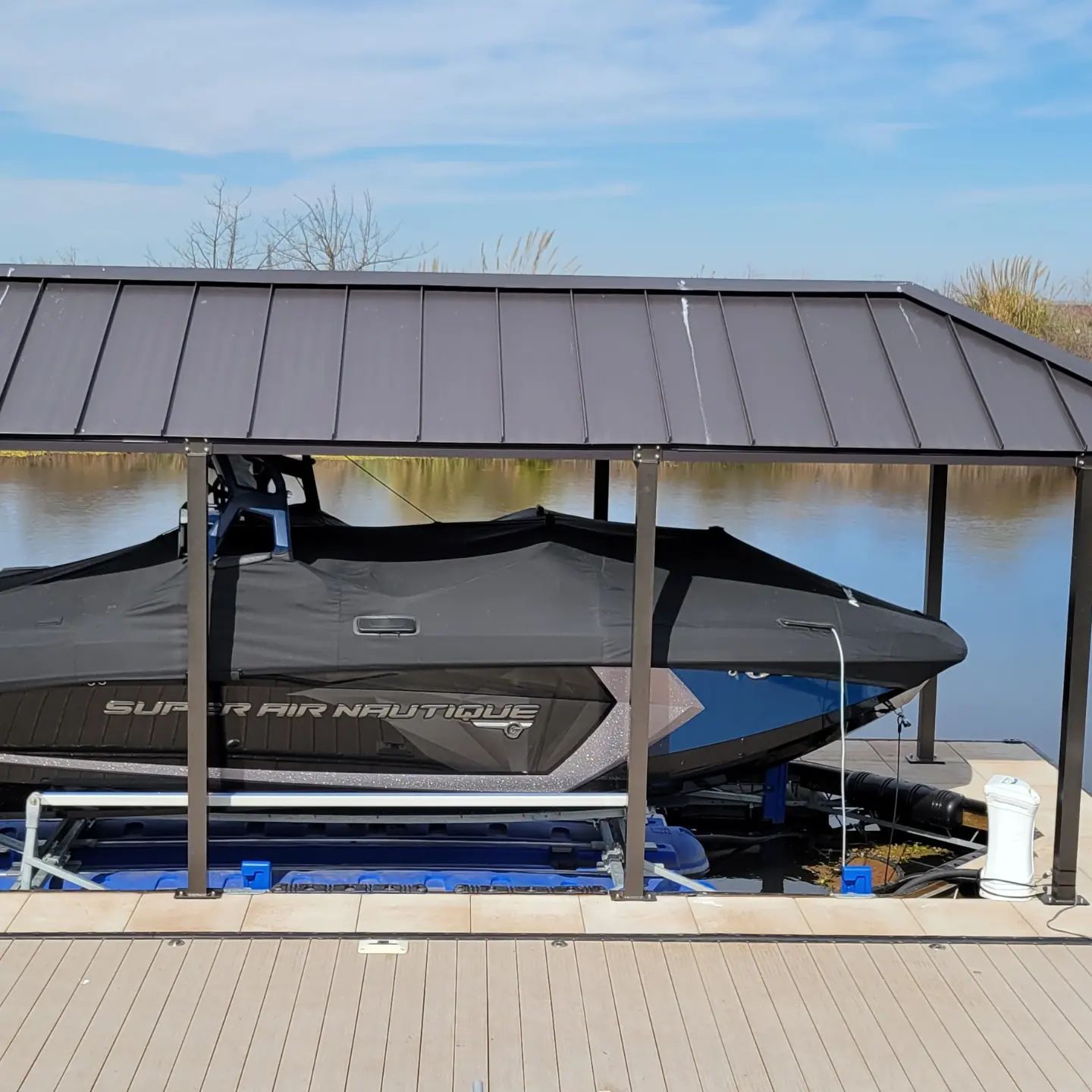 A boat is sitting under a covered dock next to a body of water.