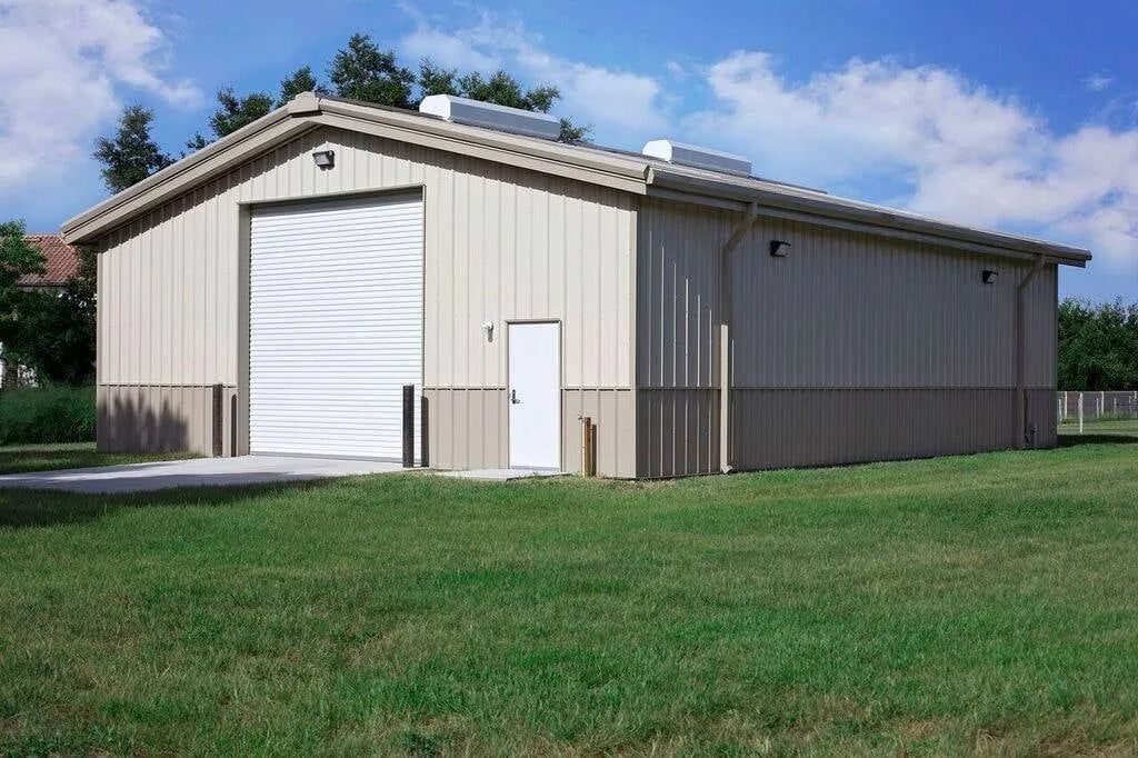 A large building with a white door is sitting in the middle of a grassy field.