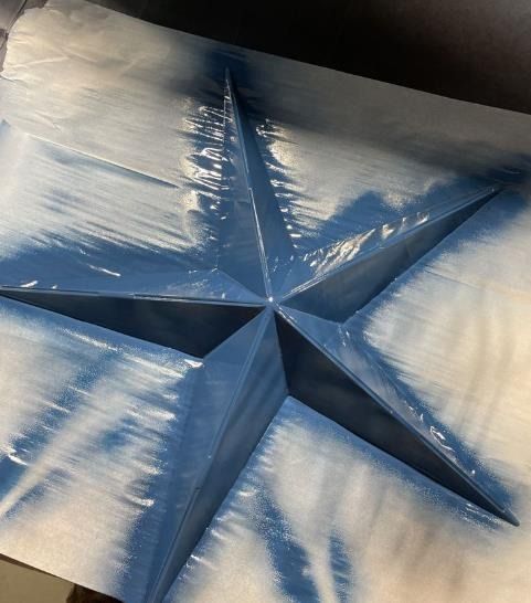 A blue and white star is painted on a piece of paper.