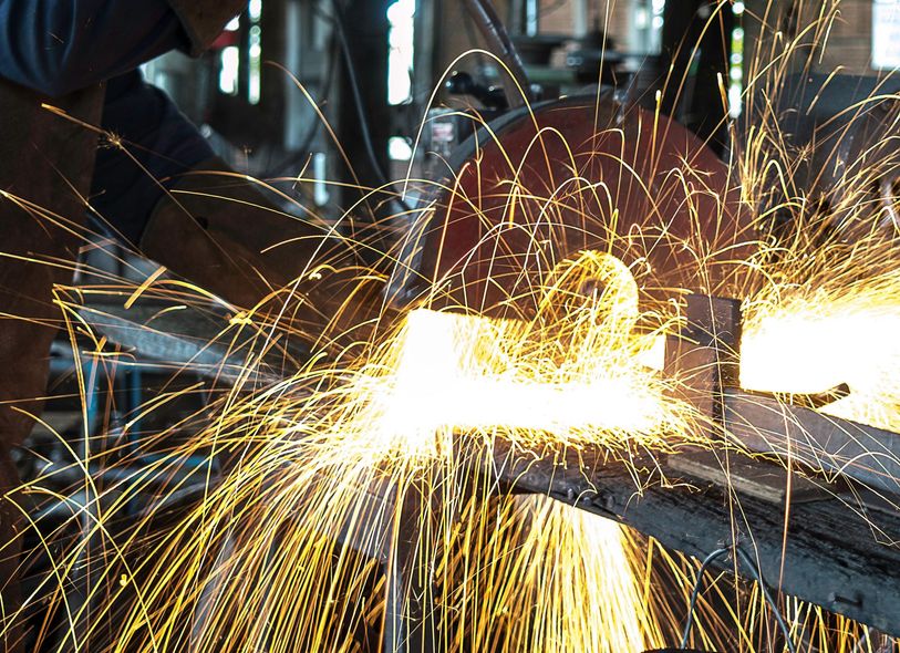 A man is grinding a piece of metal with sparks coming out of it