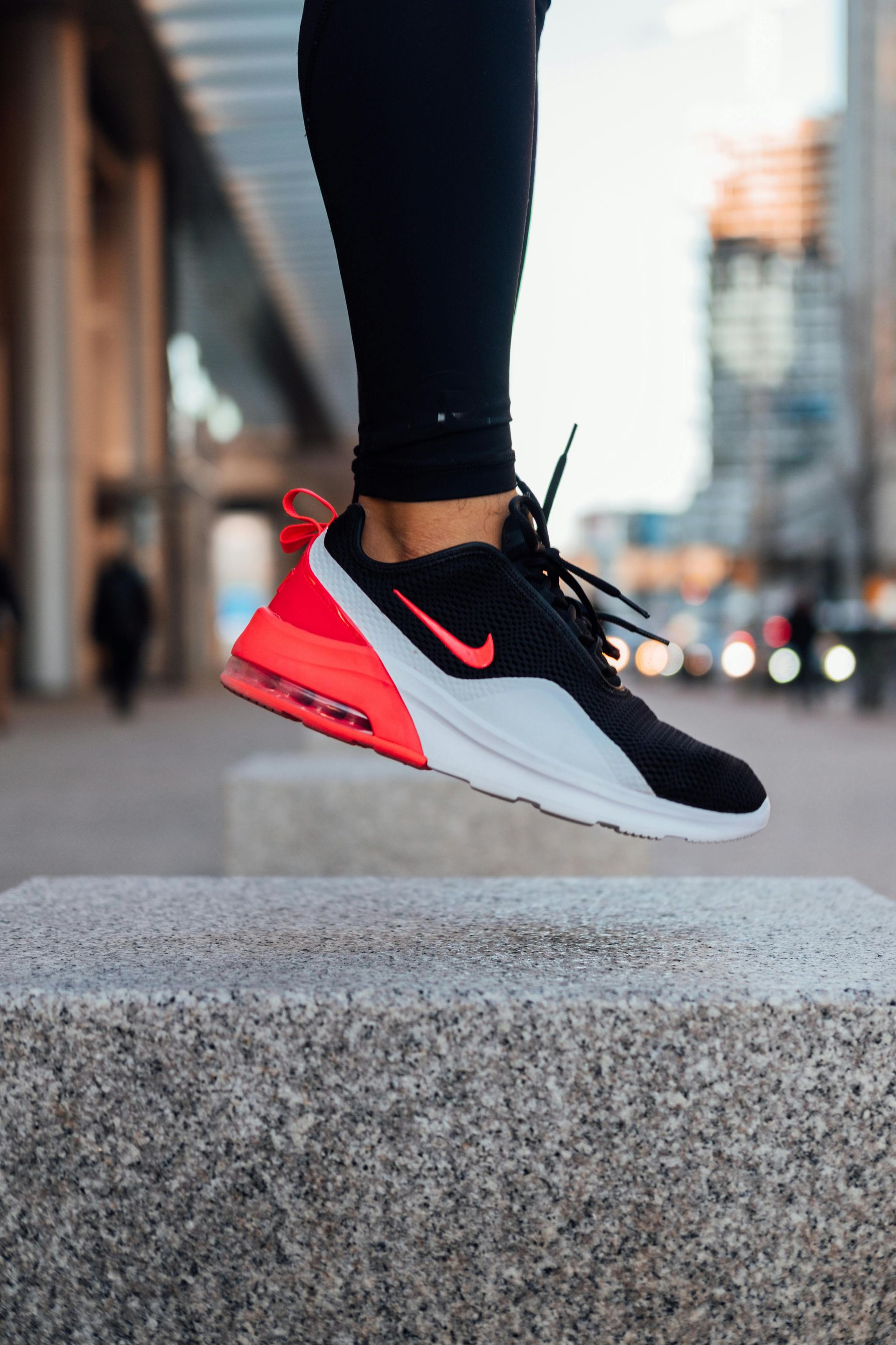 A SINGLE, SNEAKERED RIGHT FOOT ELEVATED ABOVE A STONE PAVEMENT.