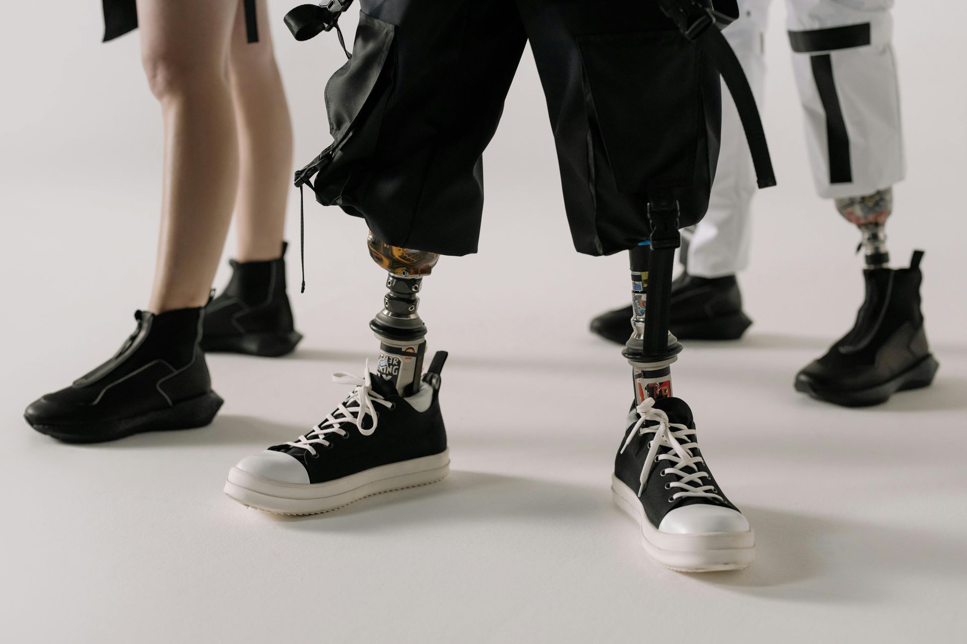 DOUBLE BELOW-KNEE-AMPUTEE WITH PROSTHETIC LEGS SPORTS A PAIR OF BLACK AND WHITE TENNIS SHOES.