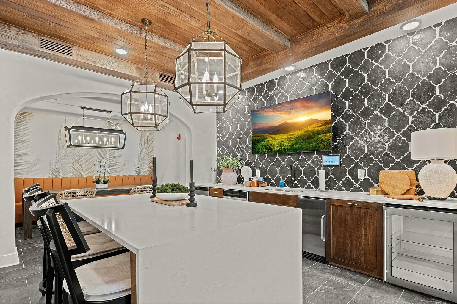 Modern apartment kitchen with a large white island, pendant lights, and a black-and-white patterned wall.
