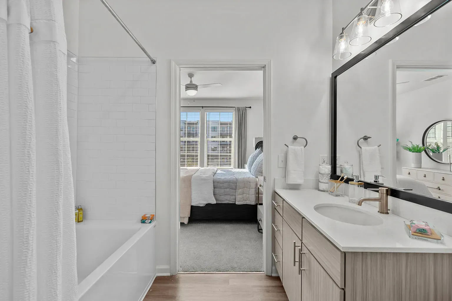 Bathroom vanity with sink, large mirror and lights, doorway to a bedroom.