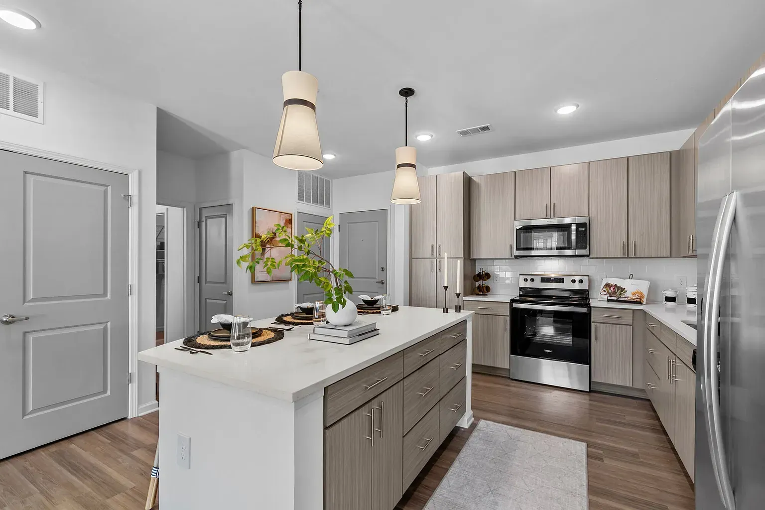 Modern kitchen with island, light wood cabinetry, stainless steel appliances.