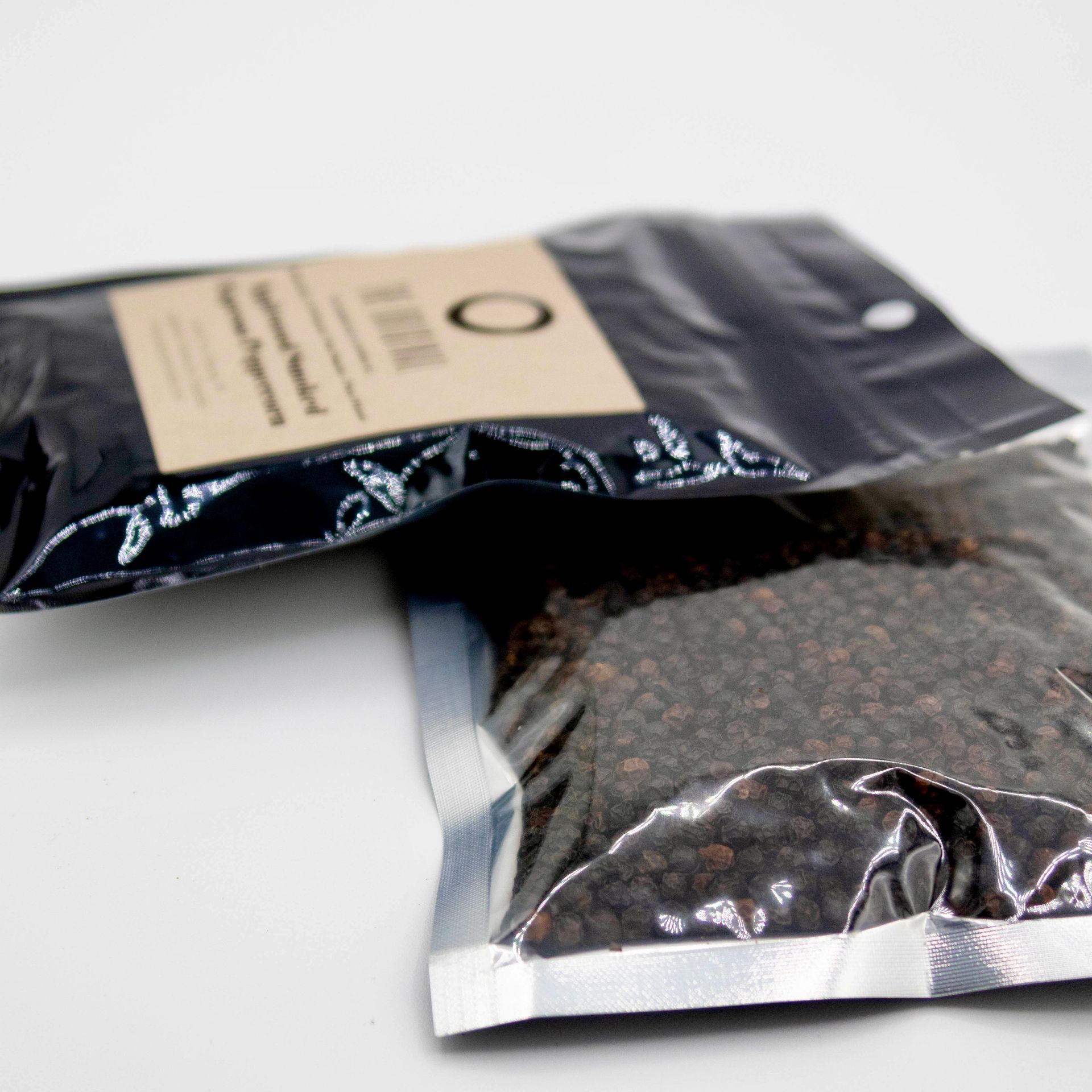 A bag of coffee next to a glass of coffee beans and a glass of wood chips