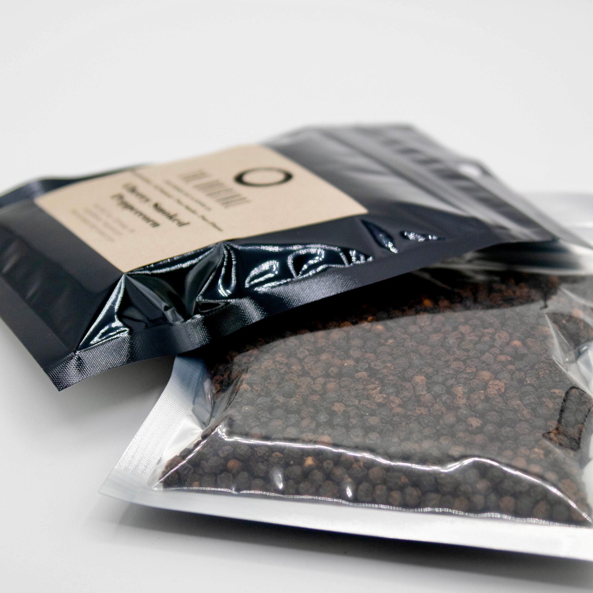 A bag of cherry smoked peppercorns next to a glass of wood chips